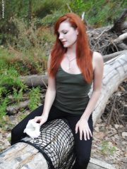 Young redhead chick Nicci Vice showing off tits and ass in the woods